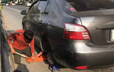 ช่างปะยางรถยนต์นอกสถานที่ กำลังให้บริการเปลี่ยนยางฉุกเฉิน 24 ชั่วโมง